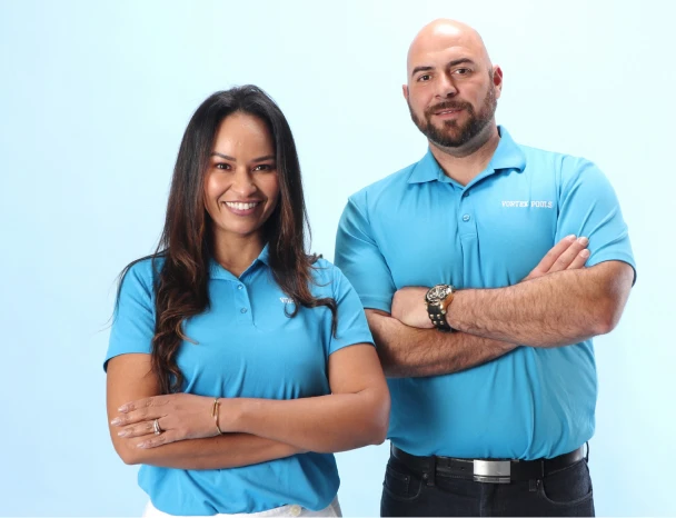 A man and a woman, Filipe and Brigida, founders of Vortex Pool, posing for a photo. In the image they have their arms crossed and wearing a blue uniform t-shirt.